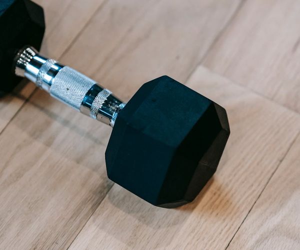 Detailed view of dumbbells and sports equipment on a dark floor.
